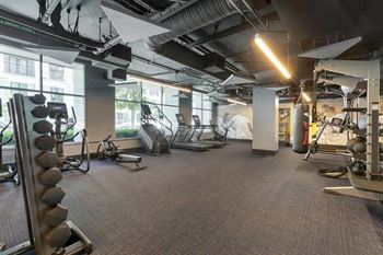 A gym with cardio equipment and windows in a building 